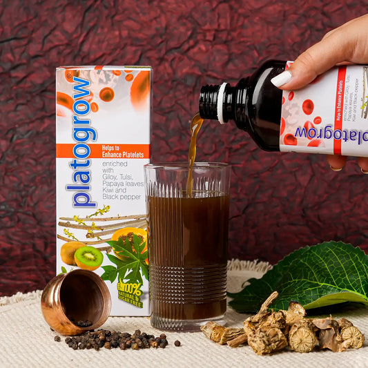 a hand pouring platogrow syrup in a glass of water, with ingredients surrounding the glass 